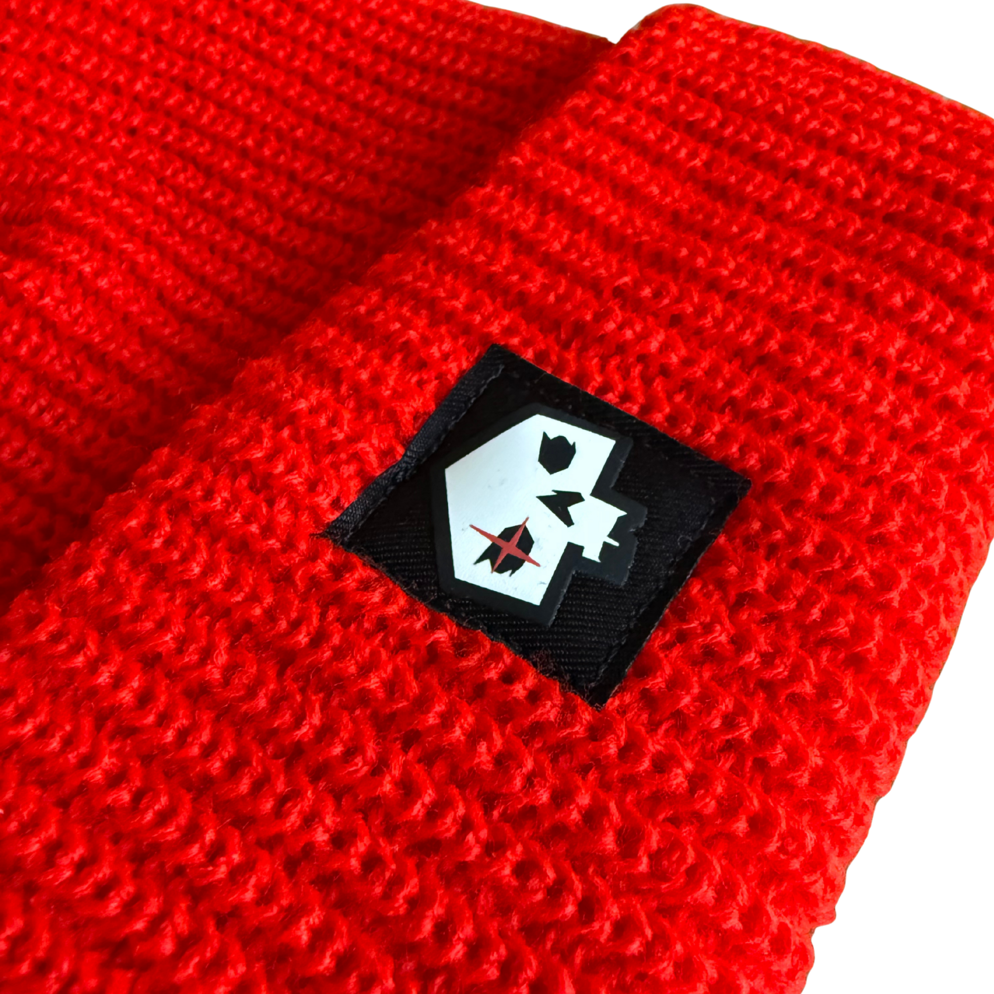 Red knitted beanie with a black patch featuring a white design on a white background